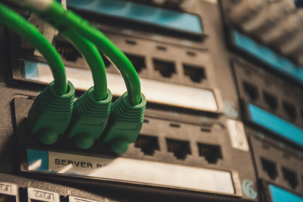 pexels-photo-1597776-1597776-1 Close-up of green network cables plugged into server ports, showcasing technology setup.